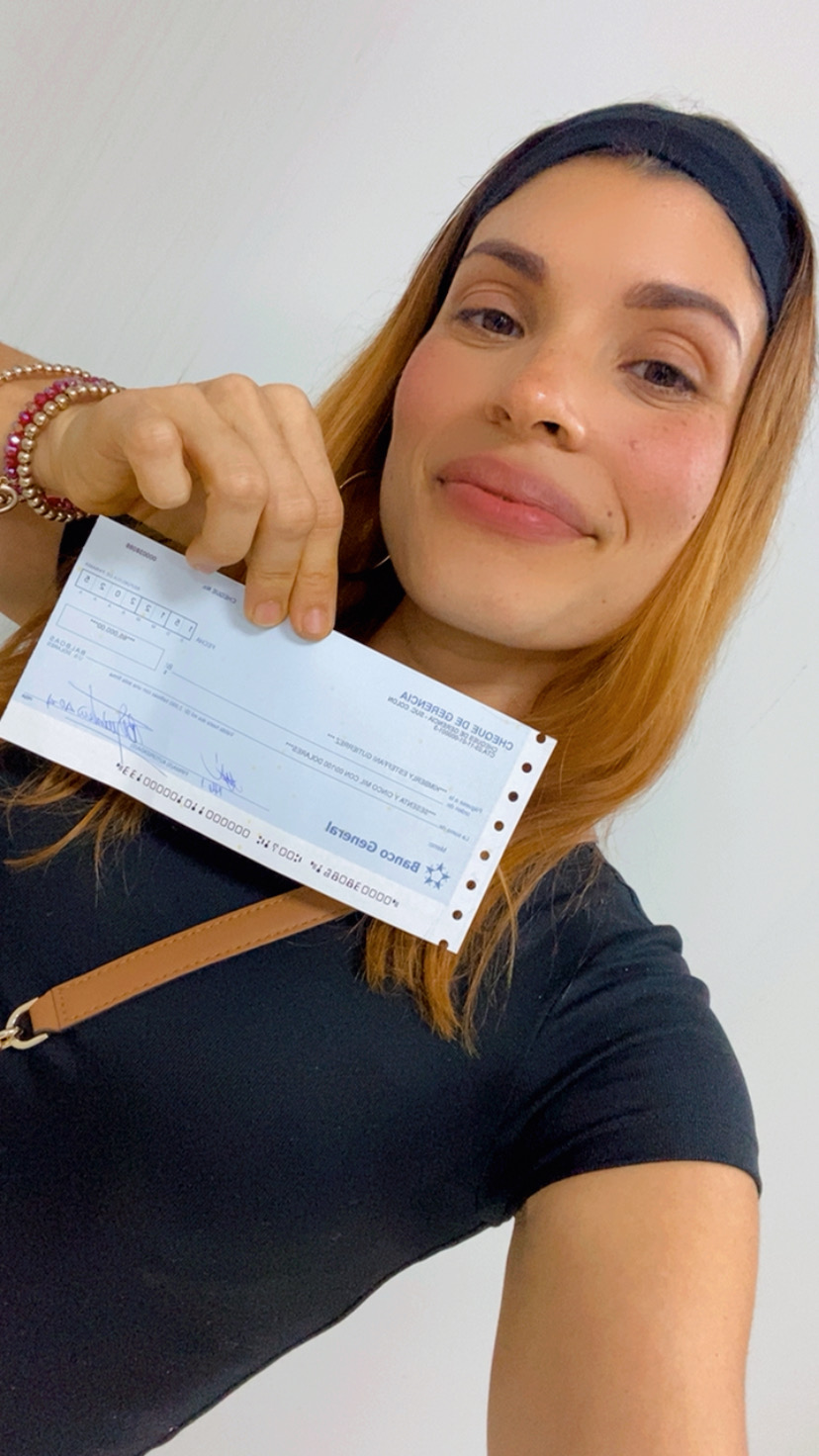Kimberly Ali sosteniendo el cheque de su venta de 65,000 dólares